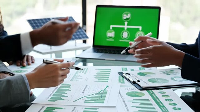 A group of people in business attire working with green graphs and charts on paper and laptop discussing energy 4k video