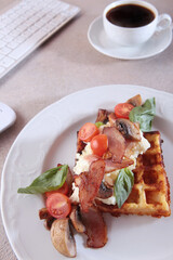 Viennese waffles with bacon, champignons and cherry tomatoes. A delicious and nutritious breakfast. The concept of a business breakfast.