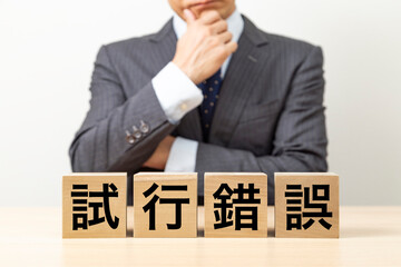 「試行錯誤」と書かれたブロックとビジネスマン