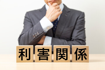 「利害関係」と書かれたブロックとビジネスマン