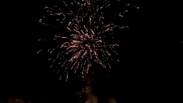 Benidorm, Spain - December 31, 2024: Spectacular fireworks display over city skyline at night, camera pans upward capturing vibrant bursts of color