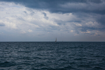 Obraz premium Yacht sailing in the Mediterranean Sea. Yachts at sea on the horizon and dramatic clouds.
