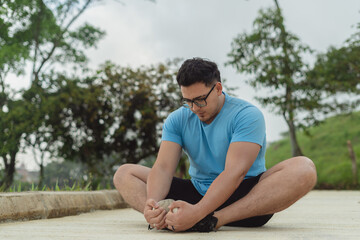 Man doing seated butterfly stretch outdoors on a cloudy day to improve flexibility and mobility