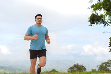 Man jogging outdoors on a hill under cloudy sky as part of cardio fitness training routine