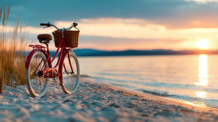 Fototapeta premium A charming red bicycle rests on the sandy beach as the sun sets over the tranquil waters, capturing a peaceful moment that invites relaxation and nostalgia for summer days.