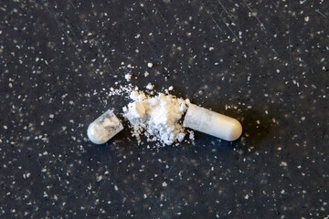 white medicine capsule open with white powder