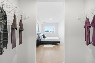 Bedroom with a white bed and a closet with clothes hanging on the rack