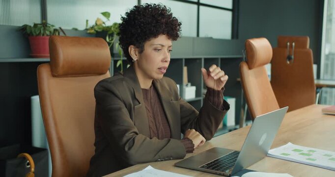 manager multitasking on laptop while reviewing reports