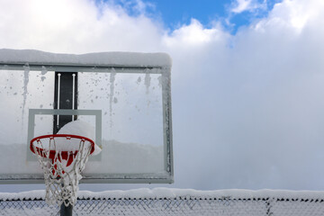Basketball hoop in winter covered in heavy snow.