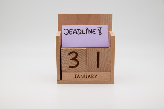 Wooden desk calendar showing 31st January with a handwritten deadline note on a paper card, symbolizing time pressure, planning, productivity, and end-of-month business tasks.