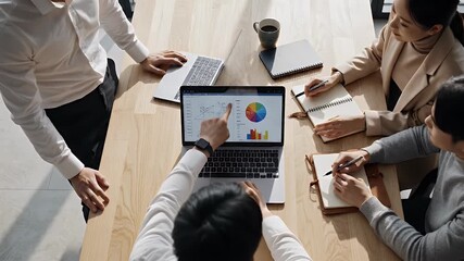 Business team collaborating around a laptop displaying financial charts and graphs during a strategic planning meeting analyzing data for growth - Powered by Adobe