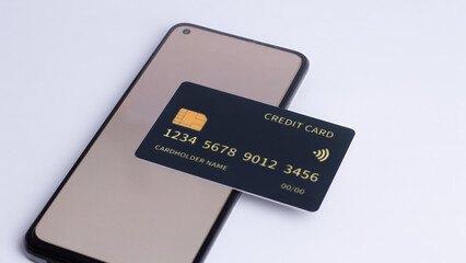 Black credit card on smartphone screen for mobile payment and online banking concept isolated on white background.
