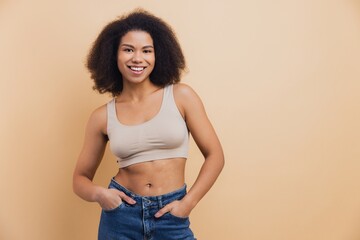 Smiling African American woman posing standing beige background