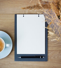 Flat lay of blank notebook page with pen and coffee on wooden table, minimal workspace concept for planning, to do lists, goals, resolutions, notes, journaling and personal organization