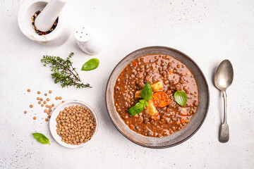 Traditional Spanish dish of lentil stew with chorizo and potatoes on a white background. Top view...