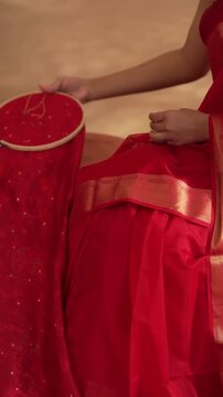 Close up of hands working on embroidering a red saree in 4K, showing detailed craftsmanship, intricate threadwork, and traditional Indian textile artistry.