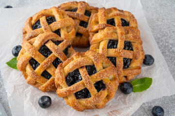 Homemade blueberry hand pies or mini tarts with milk on a concrete background.
