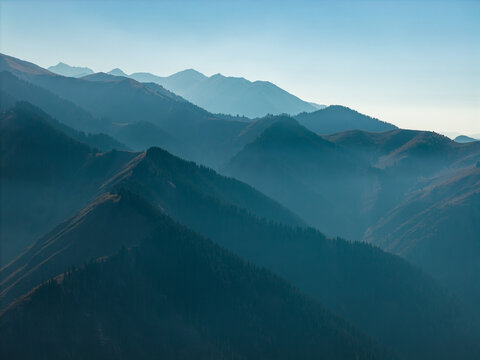 Blue layered mountain ranges in haze under clear sky, minimalist atmospheric landscape panorama - Powered by Adobe