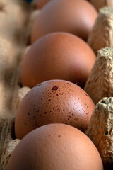 Macro shot capturing the textured brown shells of free-range organic eggs nestled in a natural, rustic cardboard egg box