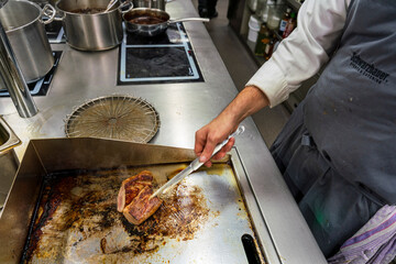 The chef at the kitchen prepare the pork fillets by grilling the meat till the steam tell its done