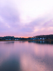 Naklejka premium Sunrise with glowing orange clouds above the Quinipiac River boat marina and forest hill in Fairhaven, New Haven County, Connecticut, United States, a radiant skyscape of light and natural beauty.