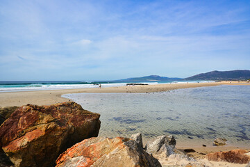 Waves crash on a sandy beach at Tarifa with rocks in the foreground