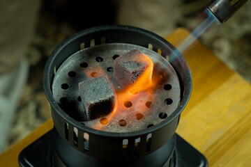 Burning coals on a grill during preparation for cooking at a gathering in the evening