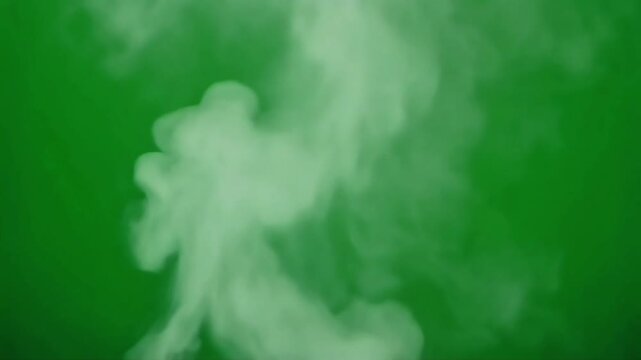 Close-up of white smoke rising against a solid green background with a shallow depth of field.