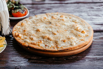 Pizza four cheeses on a wooden board in a restaurant. 