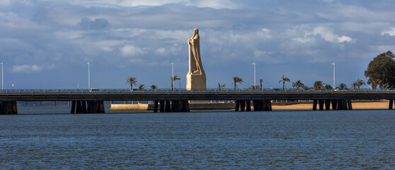 Striking stone monument to Columbus and mariners on the Odiel-Tinto river confluence in Huelva, Spain, under dramatic skies. Historic travel landmark.