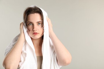 Fototapeta premium Beautiful woman drying hair with towel on light grey background. Space for text