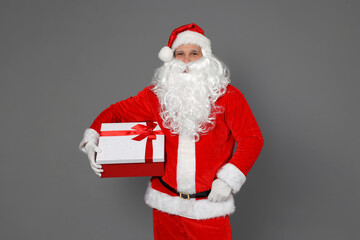 Santa Claus with Christmas gift on grey background