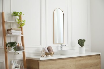 Bathroom with stylish mirror, vessel sink and houseplants. Interior design