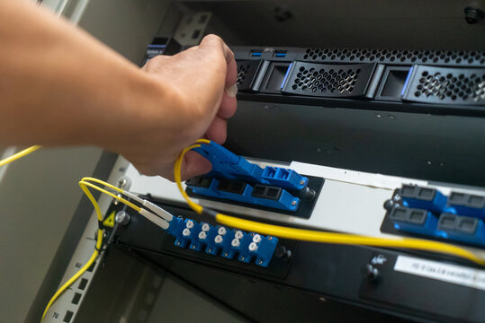 Network Technician Connecting Cables in Server Rack - Powered by Adobe