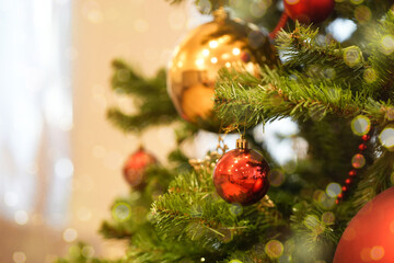 Close-up view of a beautifully decorated Christmas tree featuring shiny red and gold ornaments, surrounded by soft bokeh lights creating a festive and warm atmosphere