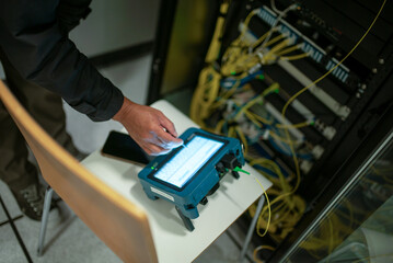 Technician Using Device in Server Room Setup
