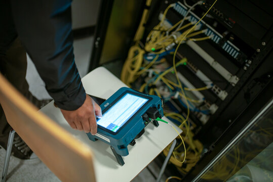 Technician Using Network Analyzer in Server Room - Powered by Adobe