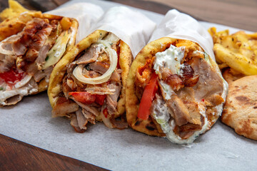 Gyros doner shawarma wraps stuffed with roasted meat, onions, tomato and tzatziki, closeup