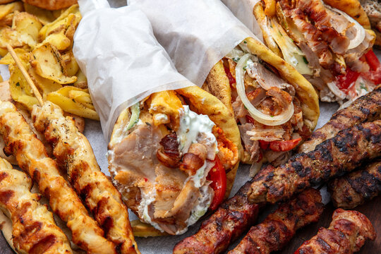 Gyro sliced meat pita bread wraps, pork skewers, and kebab, traditional greek food platter, closeup