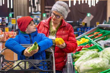 Grandmother and Grandson Choosing Fresh Vegetables Together at Supermarket Produce Section. healthy eating habits, intergenerational bonding, family shopping, conscious food choices, and everyday life