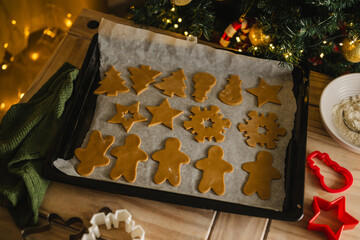 Holiday background. Uncooked raw Christmas gingerbread cookies on baking tray, lifestyle