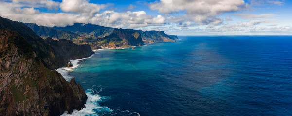 Daylight view of Madeira north coast cliffs by Ponta de Sao Lourenco, turquoise shallows to deep blue, small coves, surf lines, wide angle composition and clear air. © Aerial Film Studio
