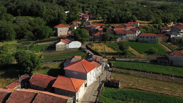 A camper minibus drives through a mountain village on a narrow serpentine road. Northern Portugal.
