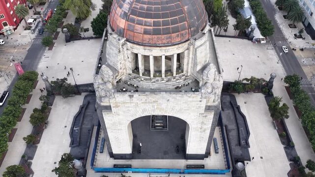 Tilt up in front of Monumento a la Revoluci&oacute;n to reveal the skyline of Centro HIst&oacute;rico and Paseo de la Reforma, drone hovering over Plaza de la Republica.