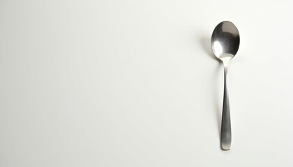 Silver spoon placed on a plain white background  