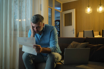 Depressed man stressed over housing costs, rent, bills, and loans sitting in living room