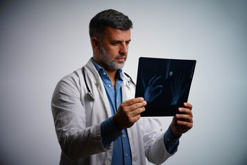 Male doctor analyzing patient’s hand X-ray in medical office