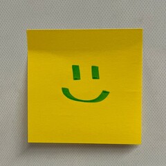 Smiling face on a yellow post it note, hand drawn smiley emoji, happy emoticon, isolated 