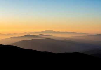Obraz premium Misty layered mountain ridges at sunrise with soft atmospheric haze