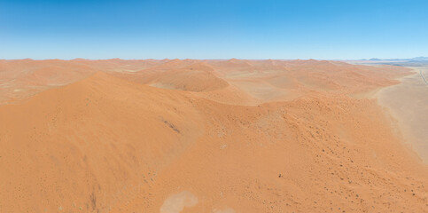 This high-quality drone photograph presents a sweeping aerial round flight over the dramatic landscapes of Namibia, offering a breathtaking bird’s-eye view of one of the world’s oldest deserts. The ca